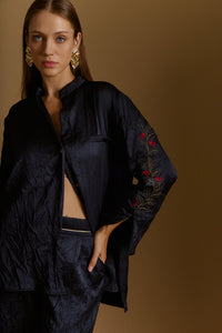 Woman wearing iRous “Niagara” crinkled fabric shirt and light jacket with Mao collar, sleeve opening, unique embroidery, and metallic buttons.