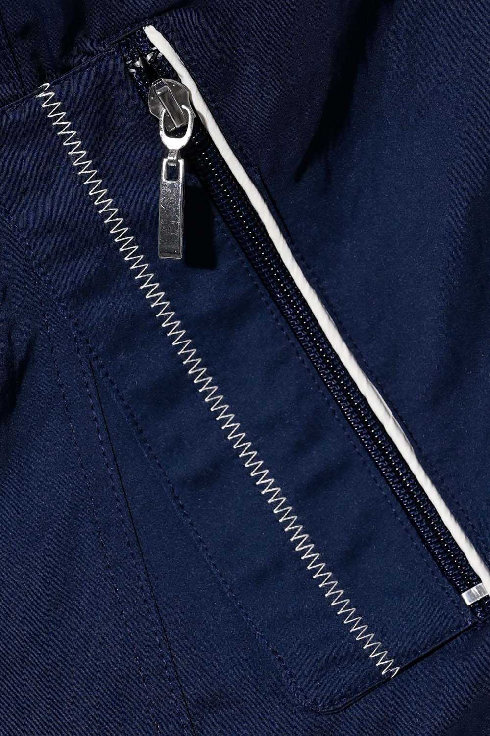 Close-up of a navy blue jacket zipper with white stitching and pull tab, showcasing functional design details.