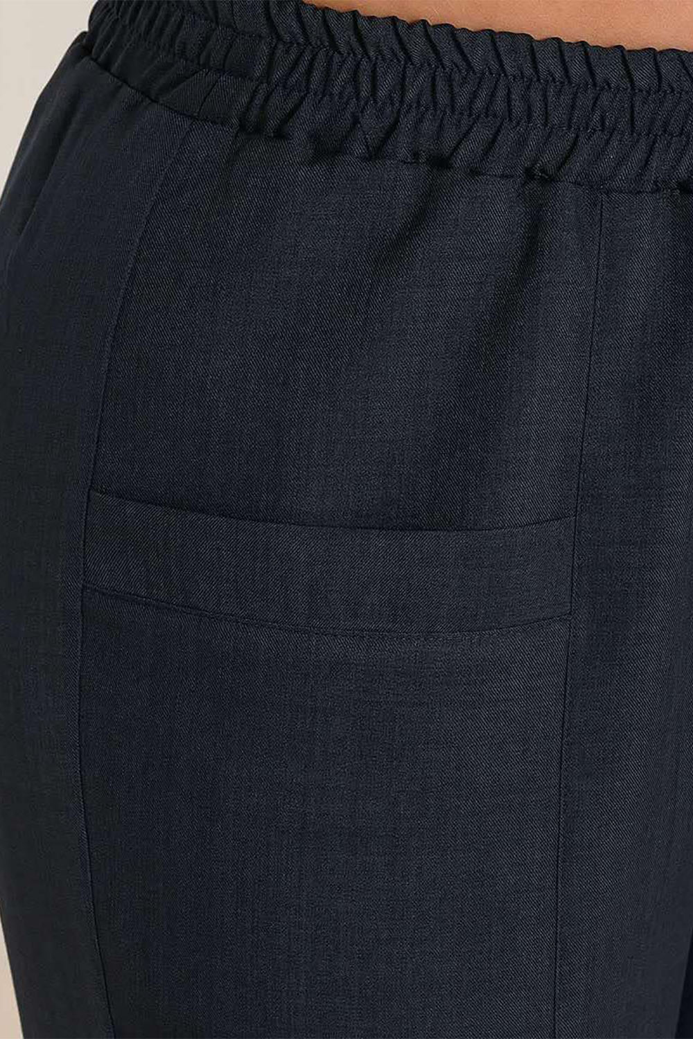 Close-up of dark blue pants featuring an elastic waistband and side pocket for comfort and style.